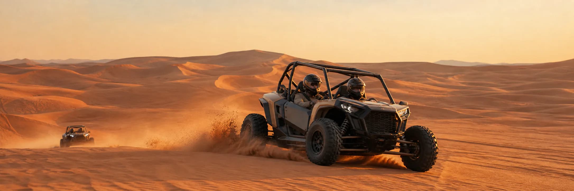 Helmeted guests crossing Dubai's red dunes in a guided dune buggy